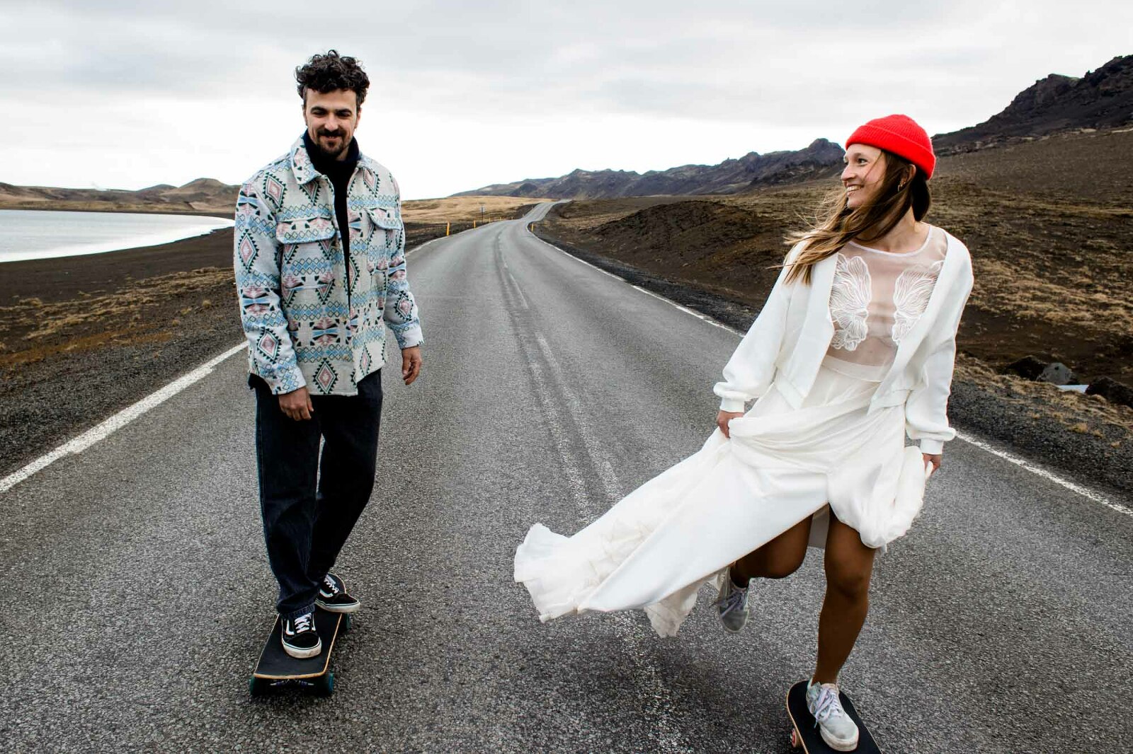 Hochzeitspaar in Island skatet mit dem Skatebaord auf einer einsamen Straße